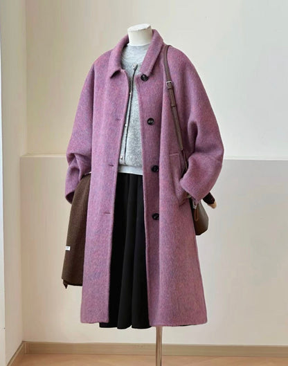 A lavender-purple wool-blend coat displayed on a mannequin, styled with a gray knit top, black skirt, brown shoulder bag, and dark brown lace-up boots on a floor stand.