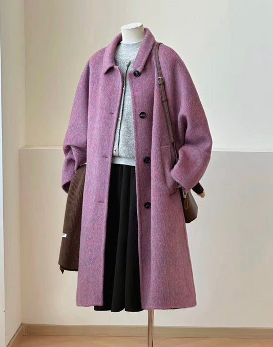 A lavender-purple wool-blend coat displayed on a mannequin, styled with a gray knit top, black skirt, brown shoulder bag, and dark brown lace-up boots on a floor stand.