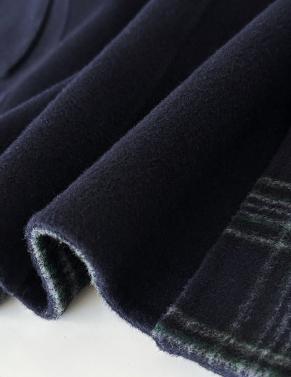 Close-up of navy double-faced wool fabric for a duffle coat, revealing a subtle green plaid interior.