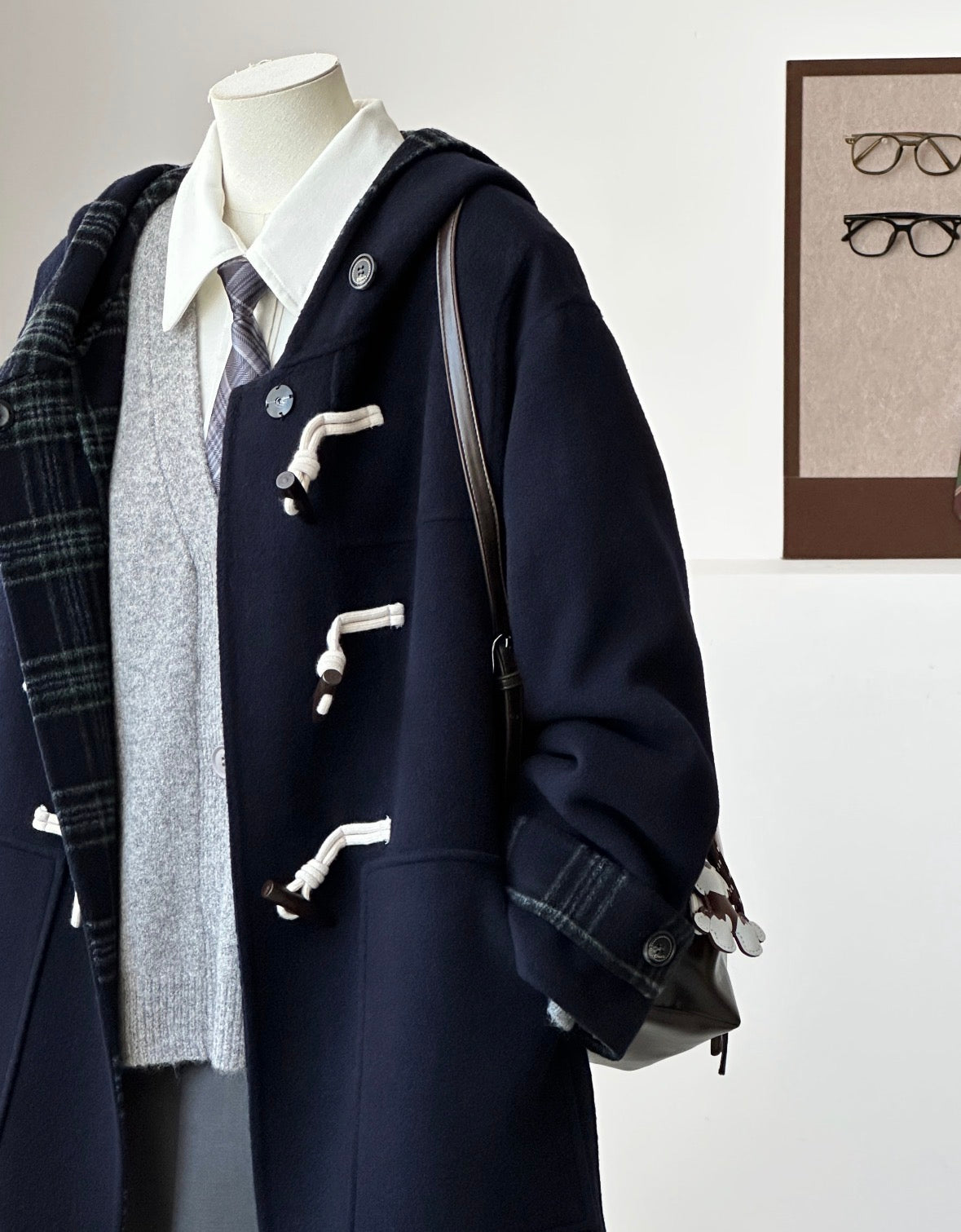 Navy Fern hooded duffle coat with plaid interior, toggle closures, and dropped shoulders on a mannequin.