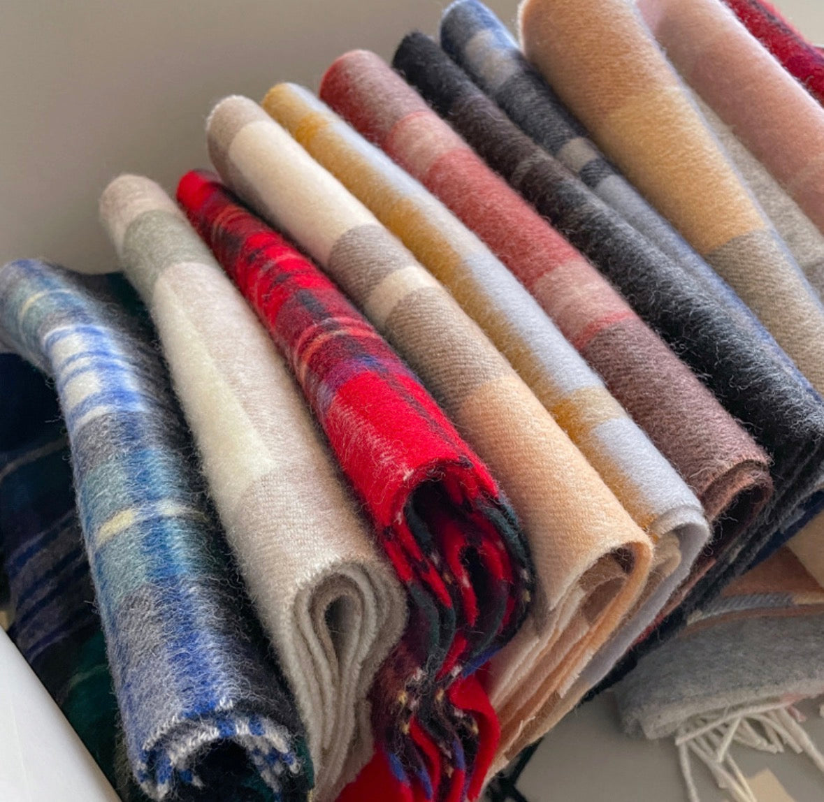 Collection of Edith 100% wool plaid scarves in various colors, including red, blue, and neutral tones.