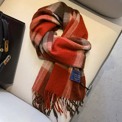 Red and brown plaid 100% wool winter scarf with fringe, folded on a chair.