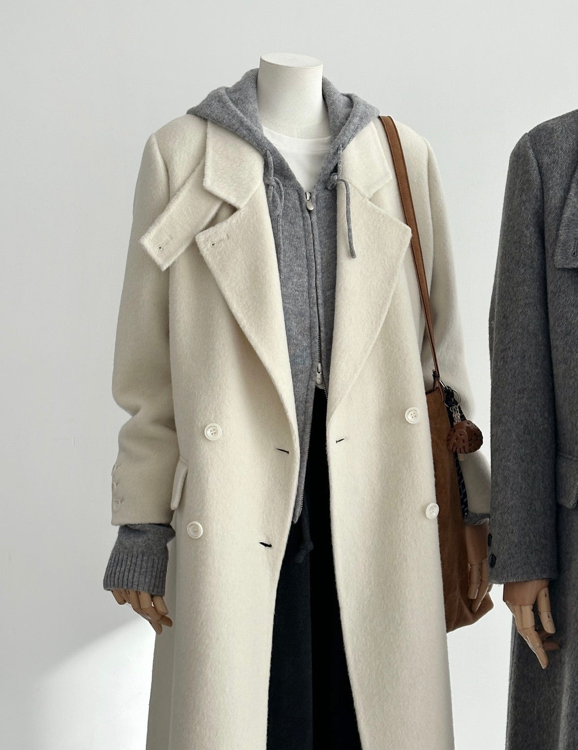 Ivory tailored wool coat with double-breasted front, convertible collar, and structured shoulders.