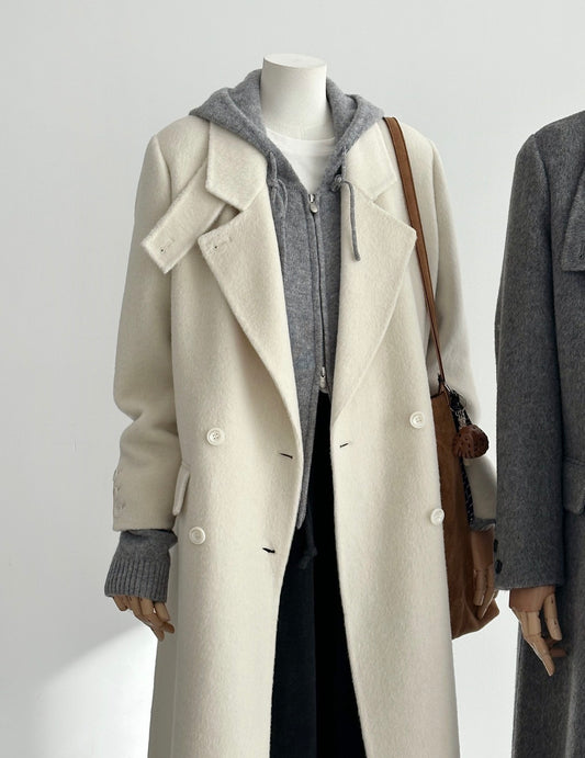 Ivory tailored wool coat with double-breasted front, convertible collar, and structured shoulders.