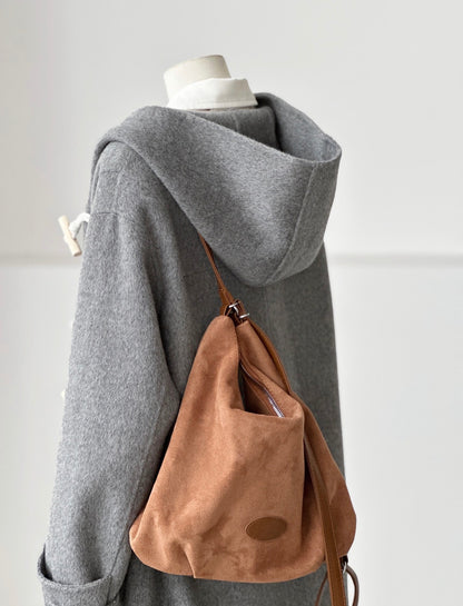 Gray Fern Hooded Duffle Coat made from double-faced wool, featuring a wooden toggle closure and a brown suede bag.